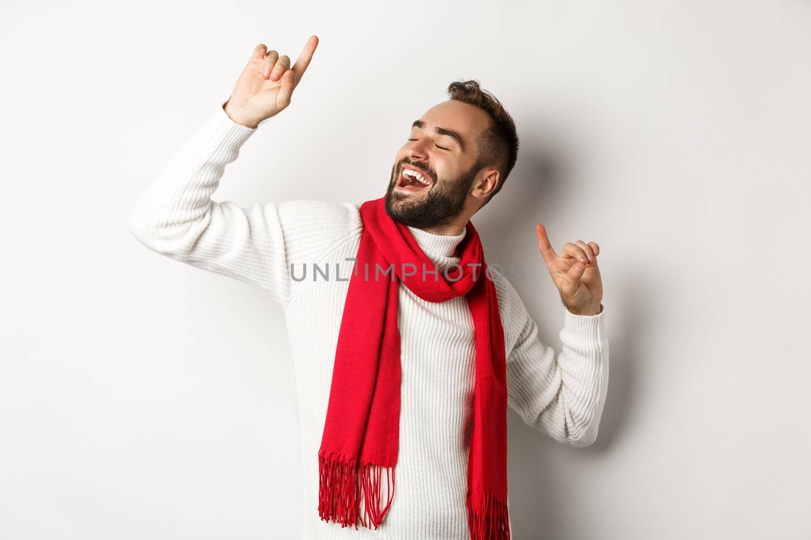 Happy man celebrating christmas party, dancing and pointing fingers, standing over white background.