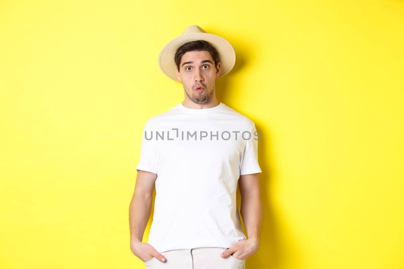 Confused guy traveller in straw hat looking puzzled, stare at camera, standing over yellow background by Benzoix