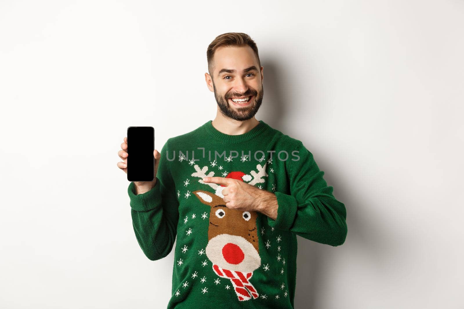 New Year, holidays and celebration. Handsome man smiling, pointing finger at mobile screen, showing app, standing over white background.