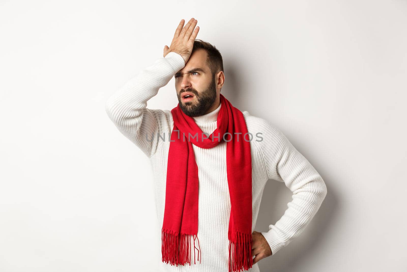 Annoyed man slap his forehead and cursing, forgetting buy christmas gifts, facepalm and standing bothered against white background.