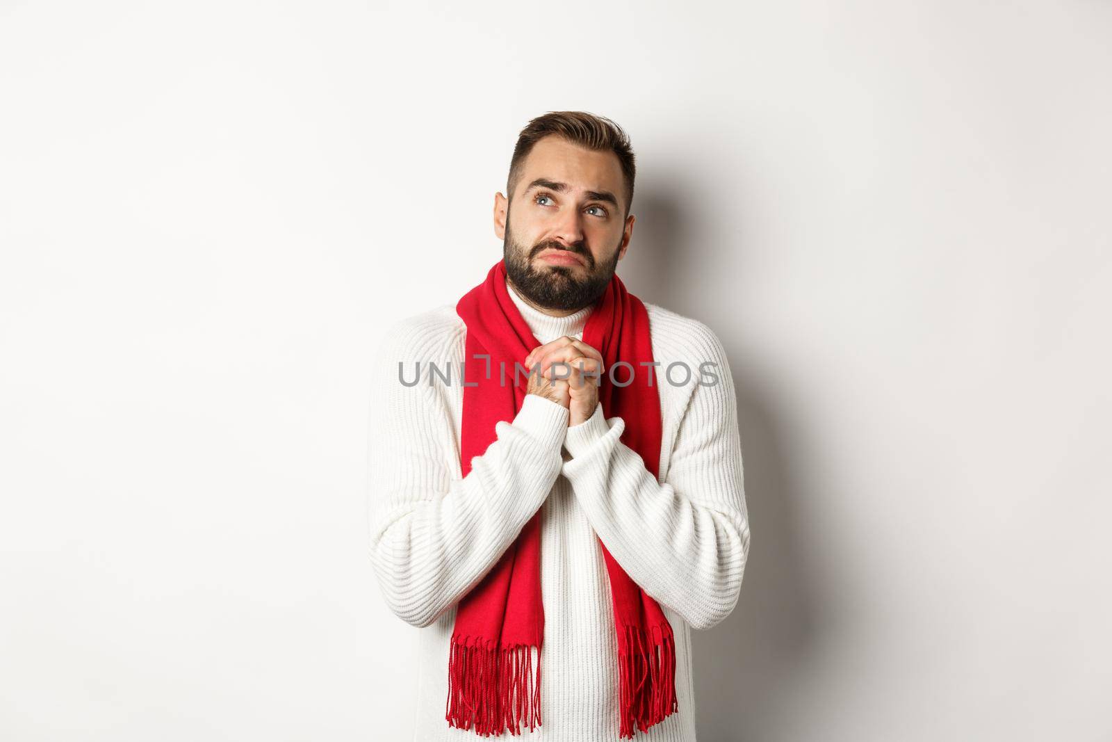 Christmas holidays and New Year concept. Sad and miserable man praying to God, making with and holding hands in pray, looking up at sky and begging, standing over white background by Benzoix