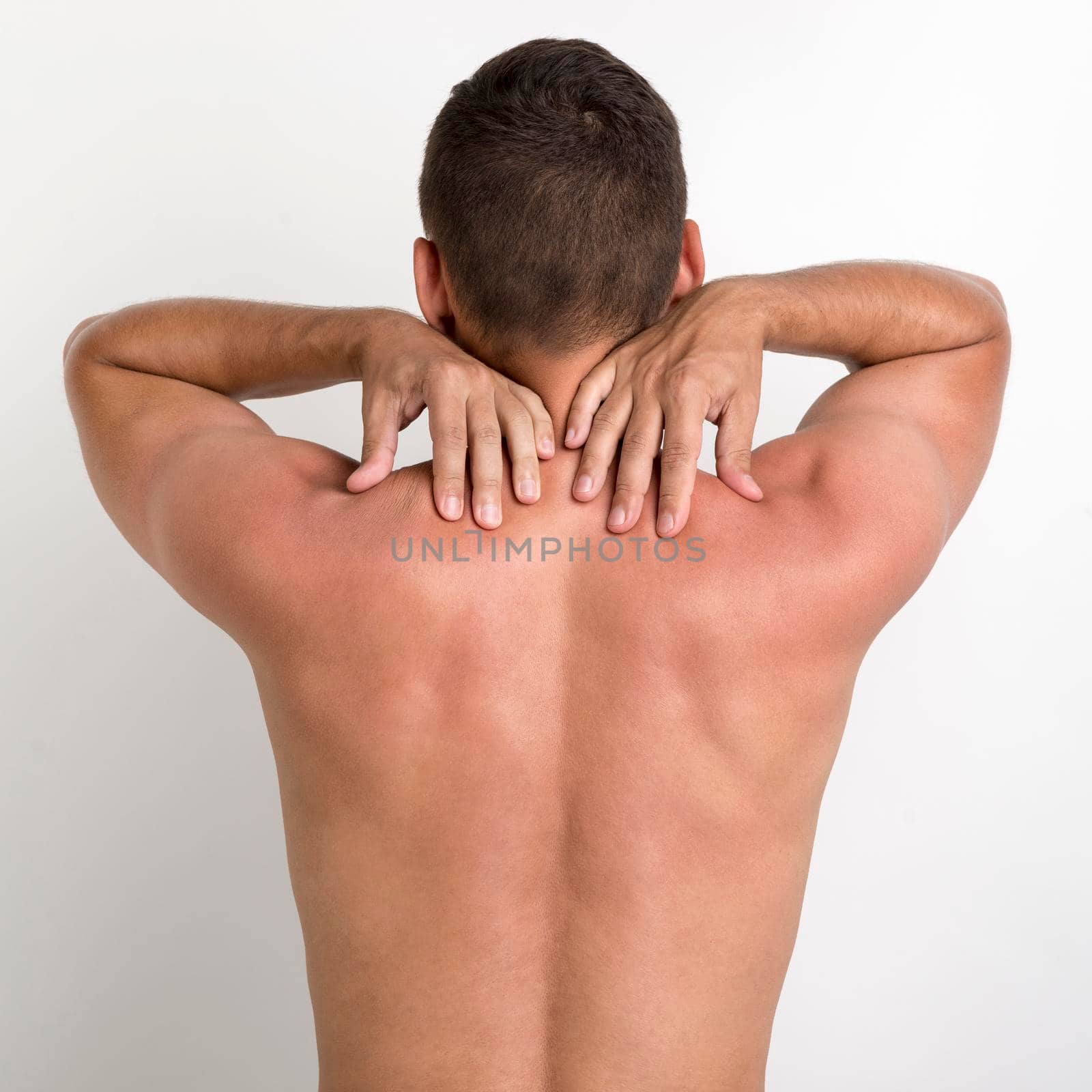 rear view shirtless man having back pain standing against white wall. High quality photo by Zahard