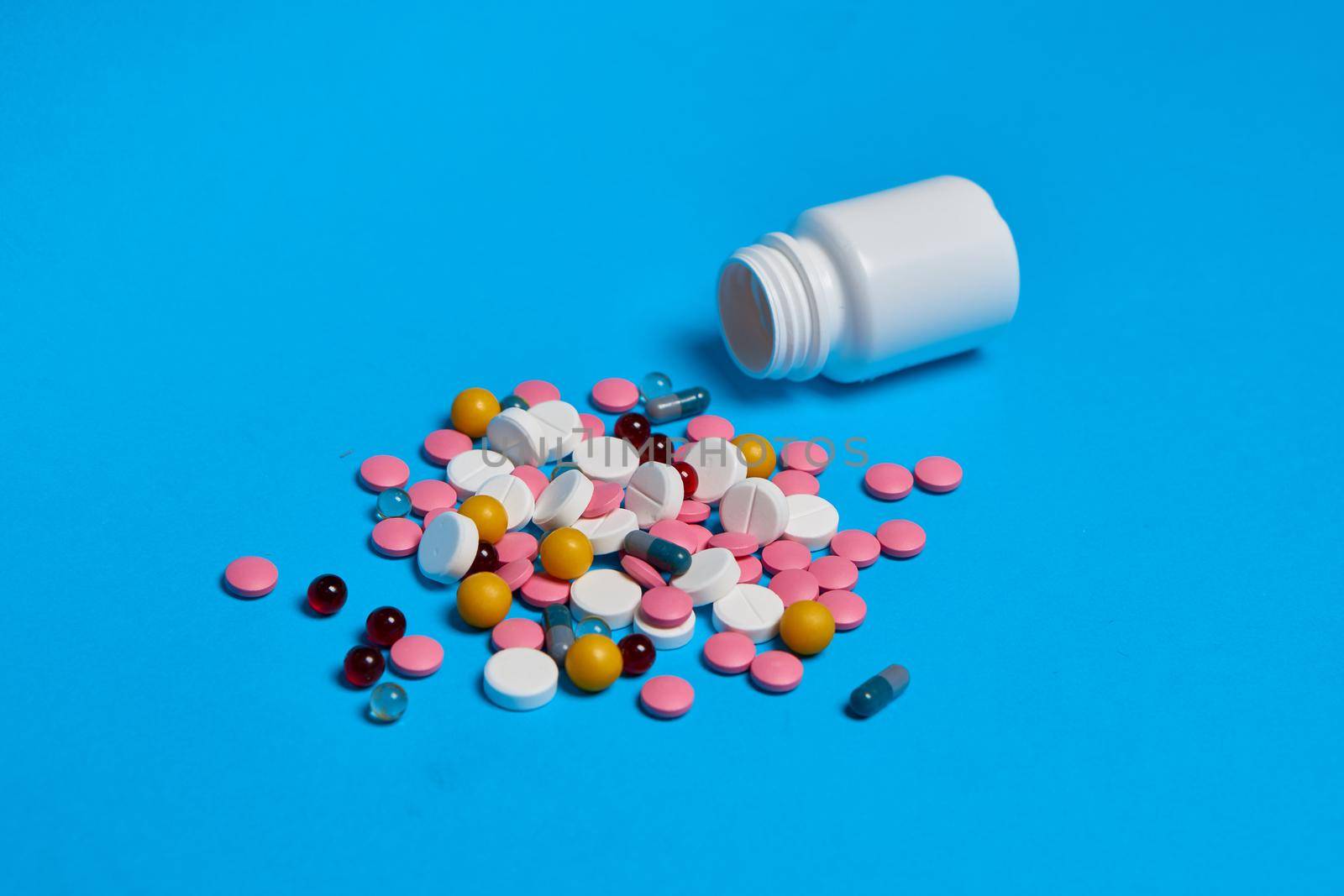 multicolored pills Pharmaceuticals medicines syringe blue background. High quality photo