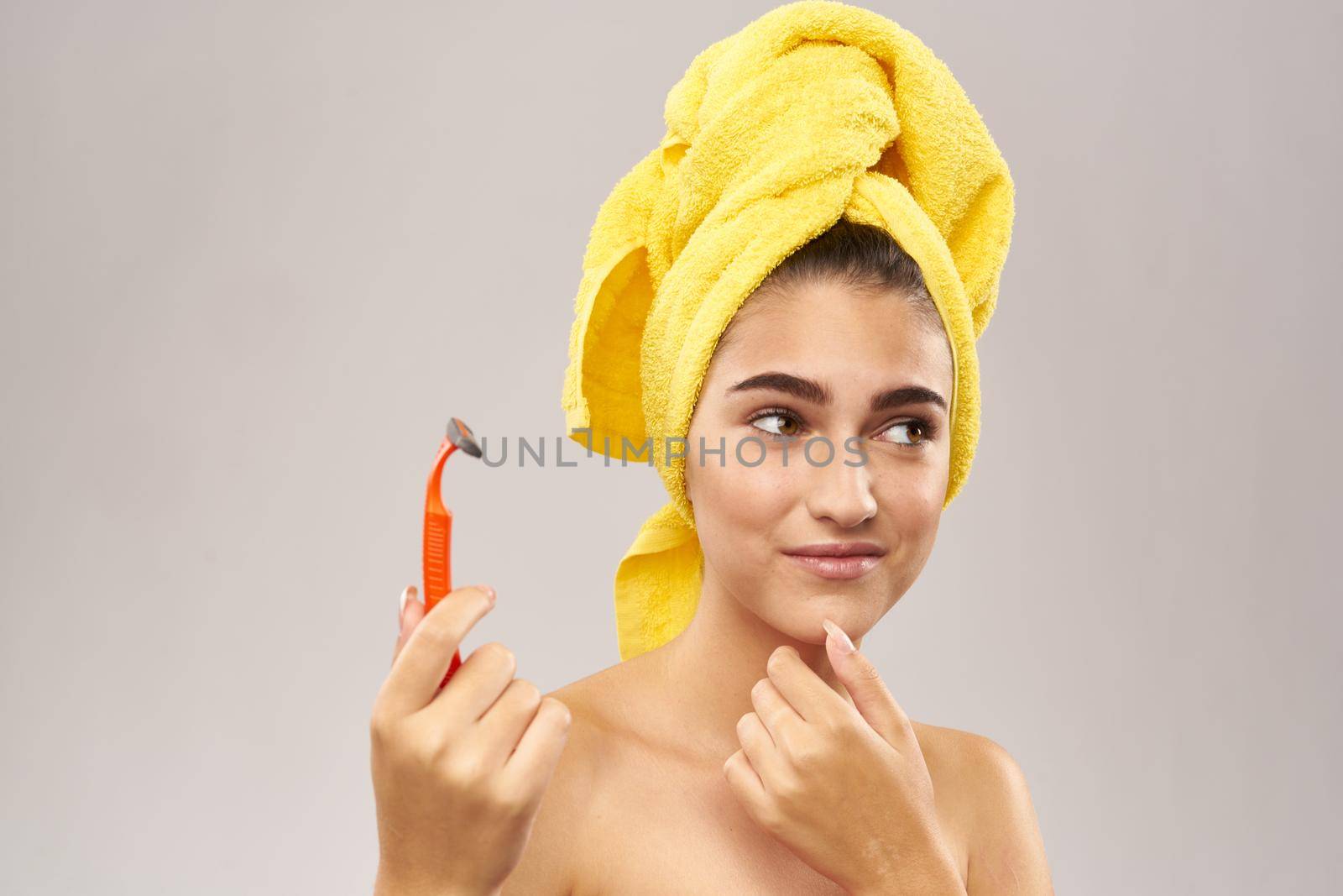 beautiful woman with a yellow towel on his head shaving. High quality photo