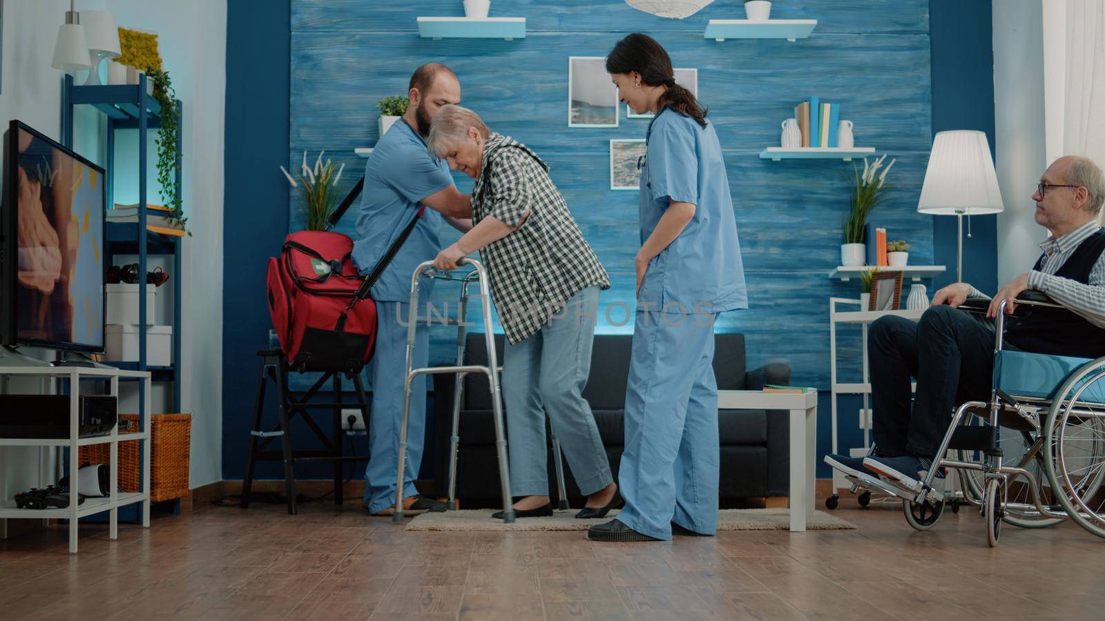 Nurses helping disabled pensioner to use walk frame by DCStudio