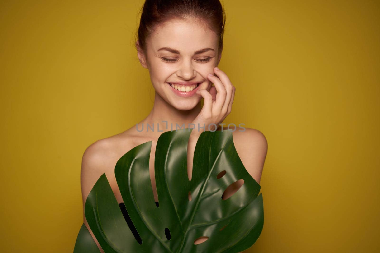 beautiful woman clean skin palm leaf cosmetics yellow background. High quality photo