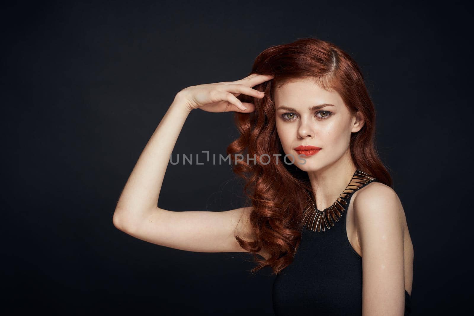 attractive red-haired woman in a black dress hairstyle dark background. High quality photo