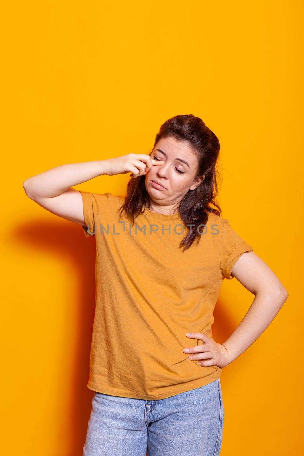 Caucasian woman rubbing hand on eyes feeling sleepy in studio. Tired person falling asleep while posing and standing over isolated background. Exhausted sleepless adult needing rest