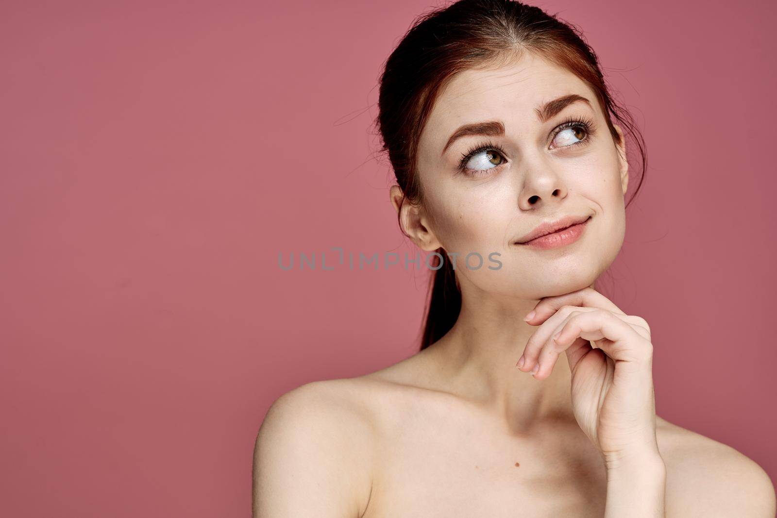 woman with bare shoulders charm cosmetics pink background posing. High quality photo