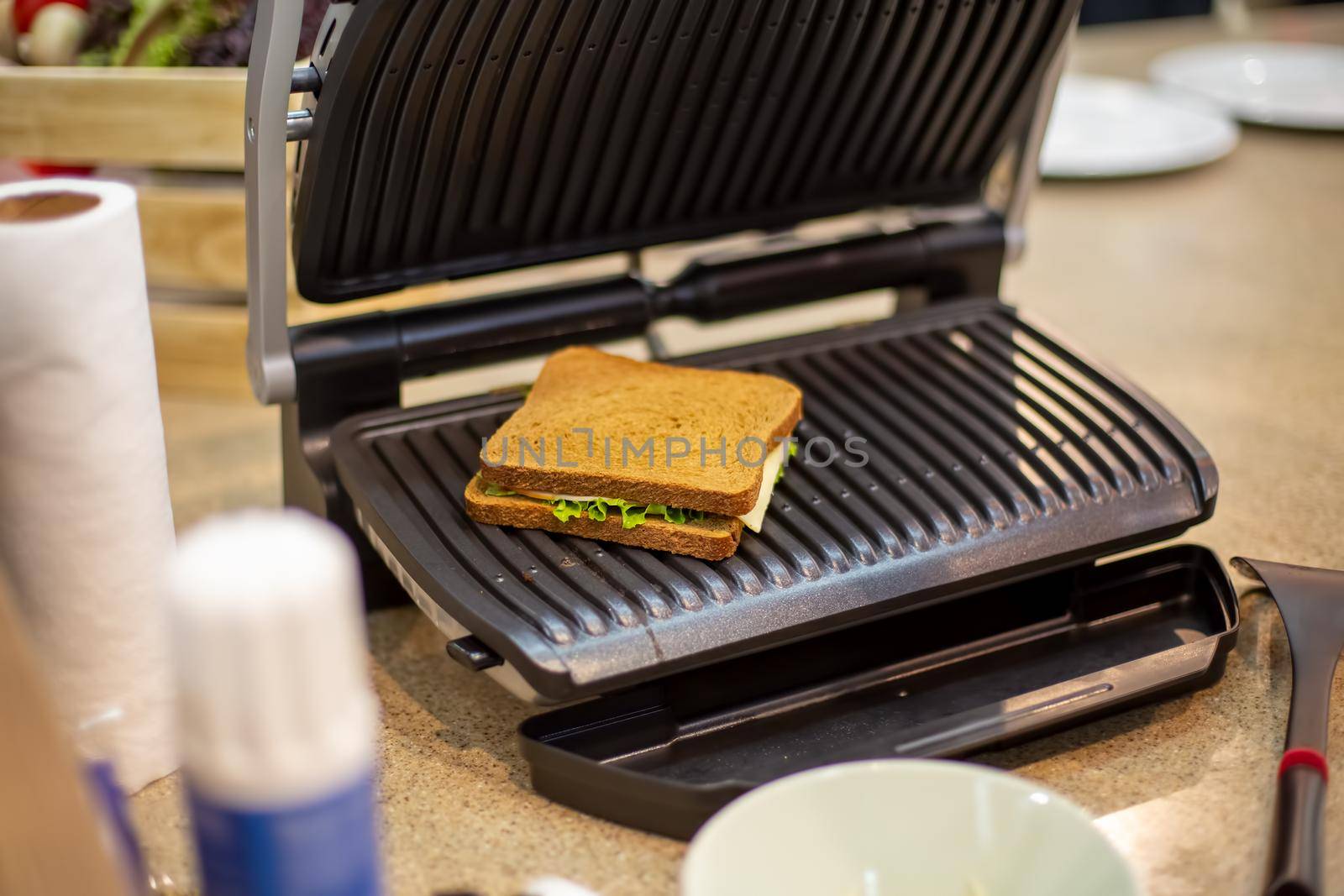delicious square grilled sandwich lies in the open electric grill close-up, soft focus, background in blur by Mariaprovector