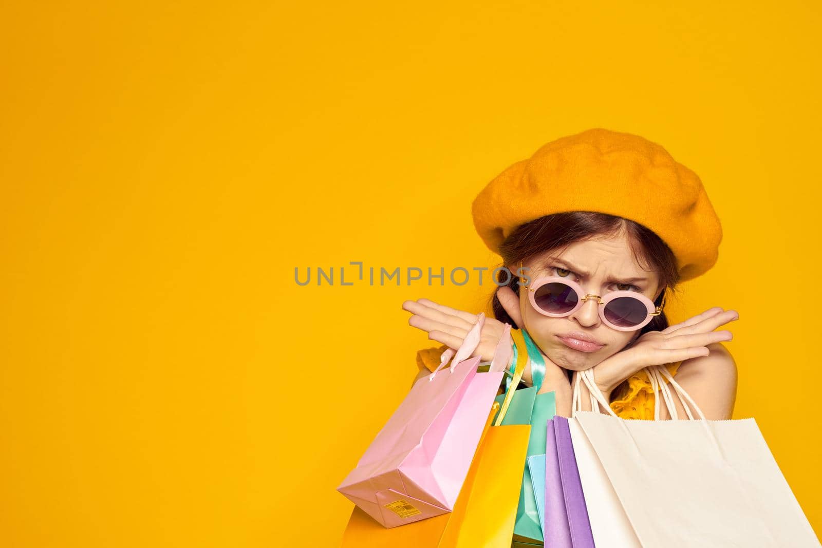 pretty woman with multicolored bags posing yellow background. High quality photo
