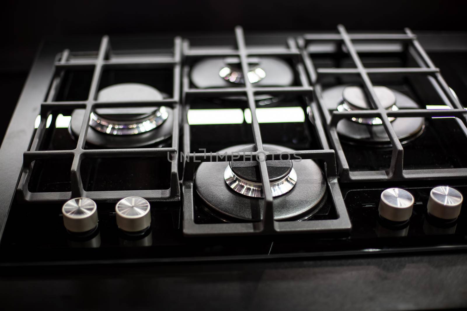 New modern black gas stove with four burners for the kitchen, stainless steel surface. Cast iron grates