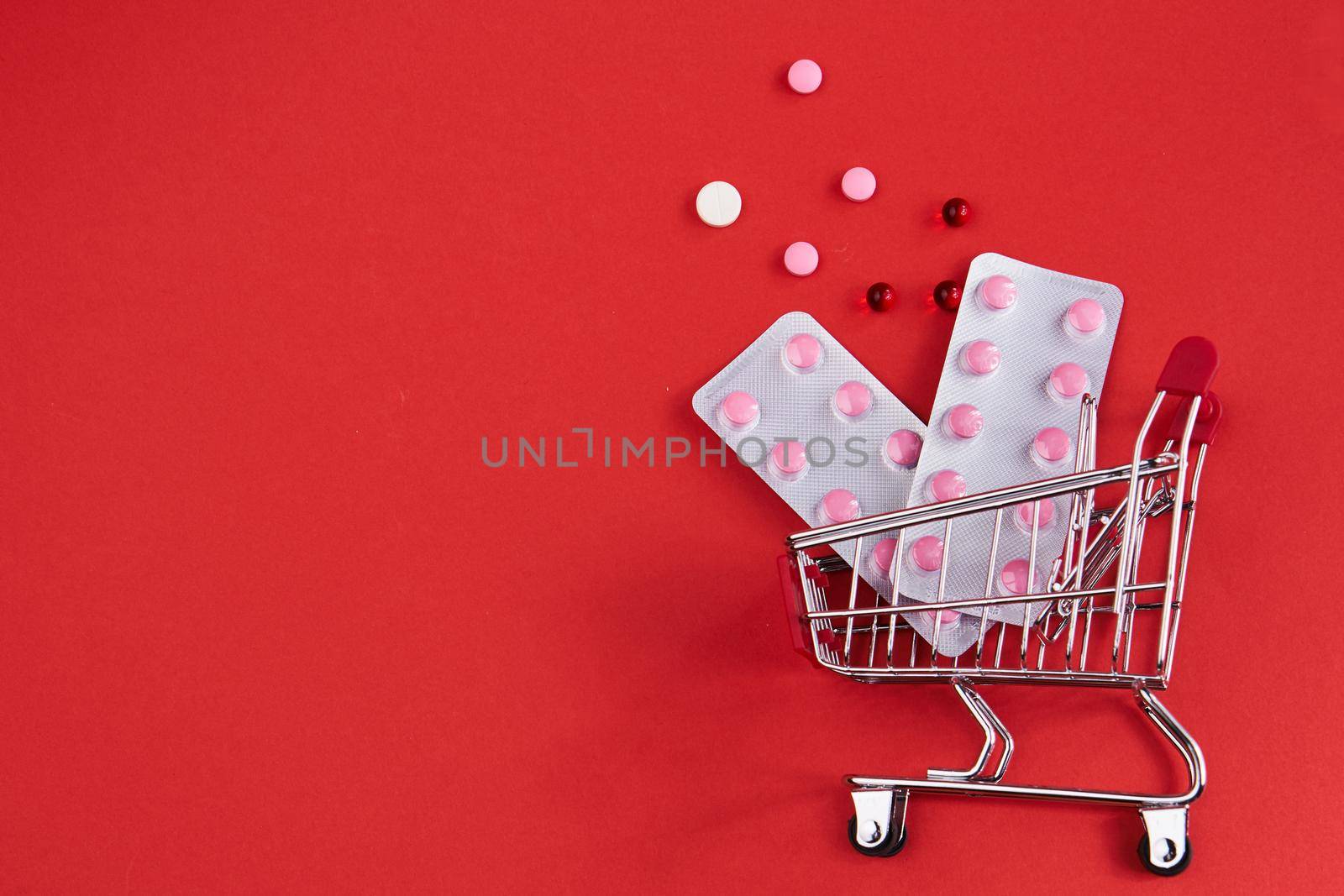 trolley with medicines on a red background Pharmaceuticals pills. High quality photo