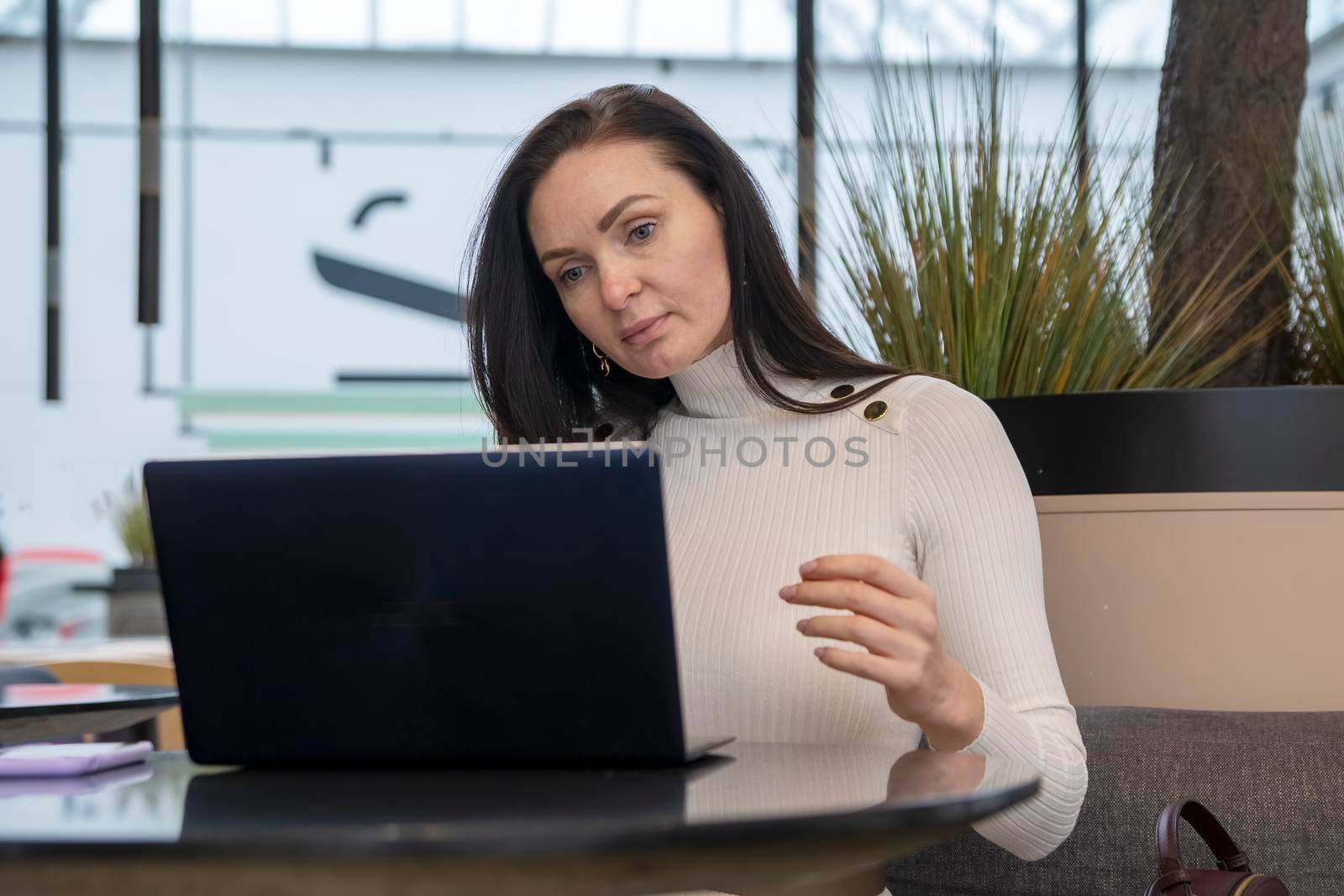 young woman with protective face mask works on laptop in cafe.