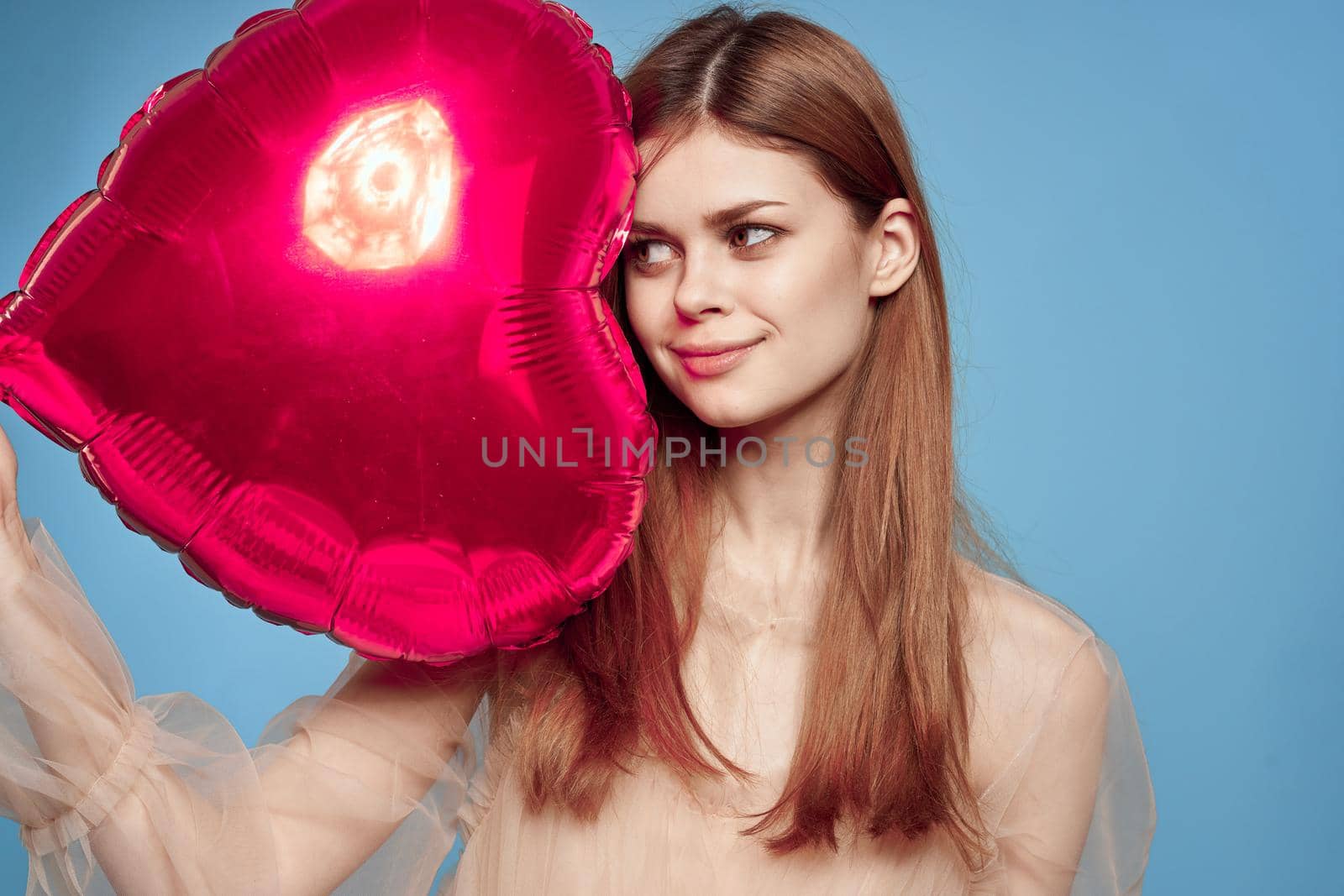 cheerful woman red heart in the hands of the balloon blue background. High quality photo