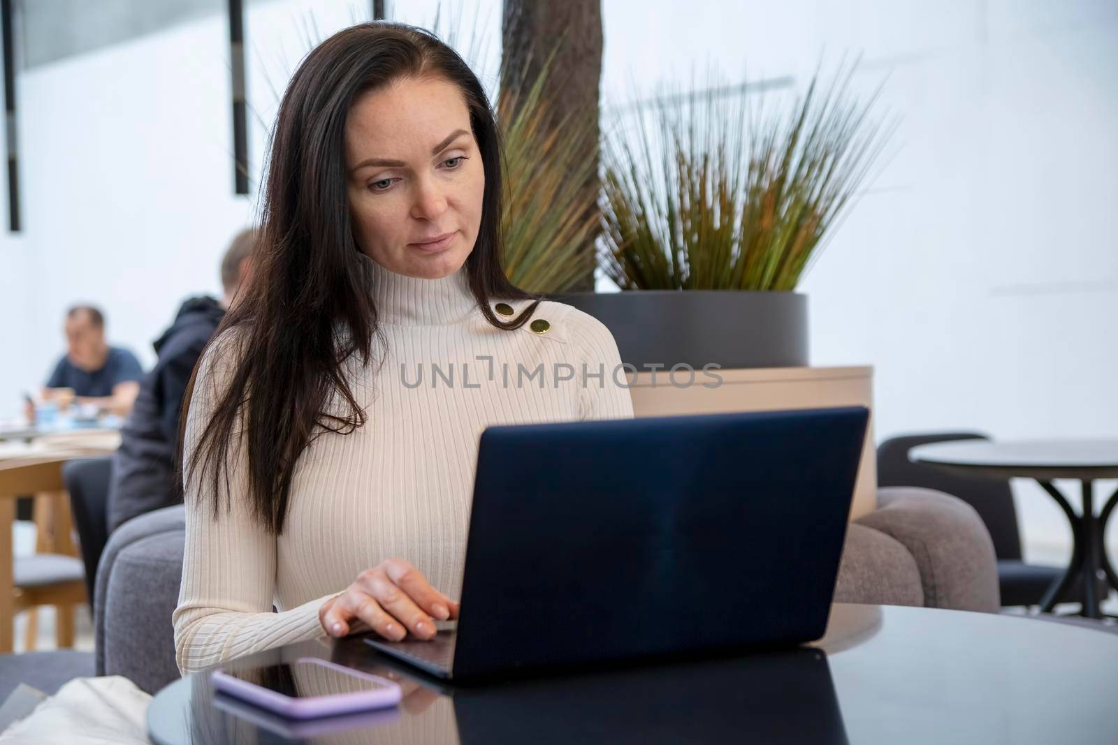 young woman with protective face mask works on laptop in cafe.