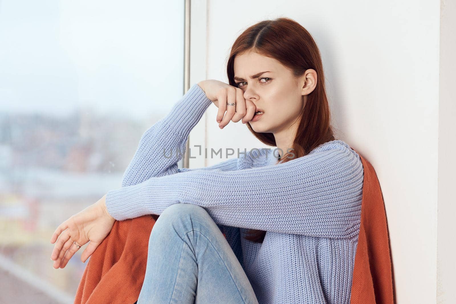 woman with sad expression sits by the window with a plaid. High quality photo
