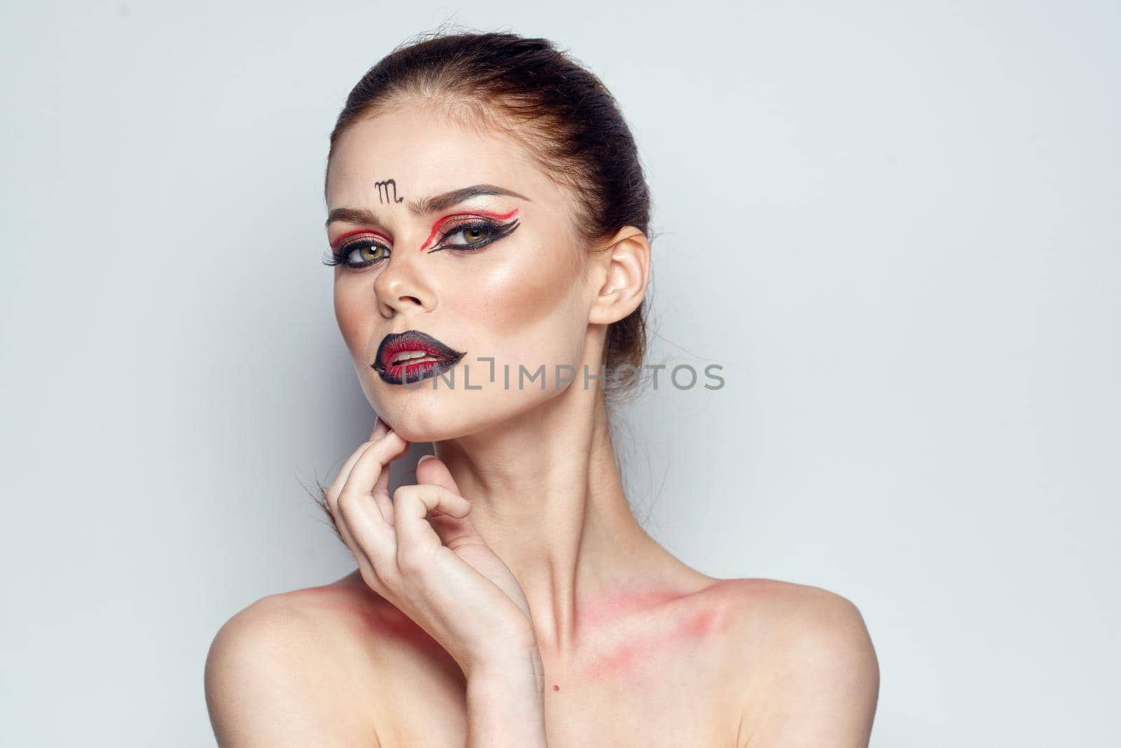attractive woman posing scorpio sign on forehead cosmetics light background. High quality photo