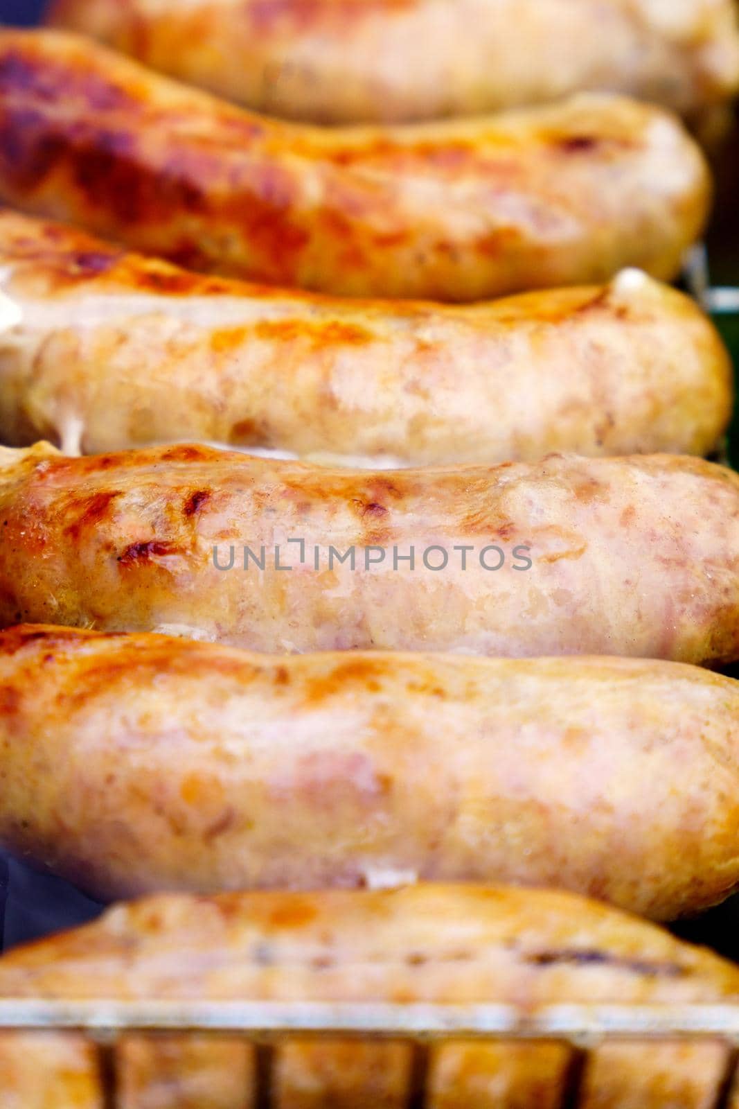 Delicious sausage close-up vertical photo on the background of the grill. Selective focus by darksoul72