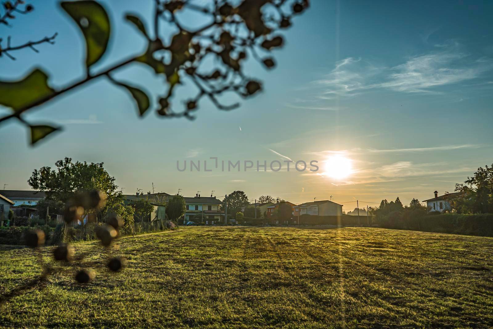 Rural landscape with beautiful gradient evening sky at sunset. Green field and village on horizon