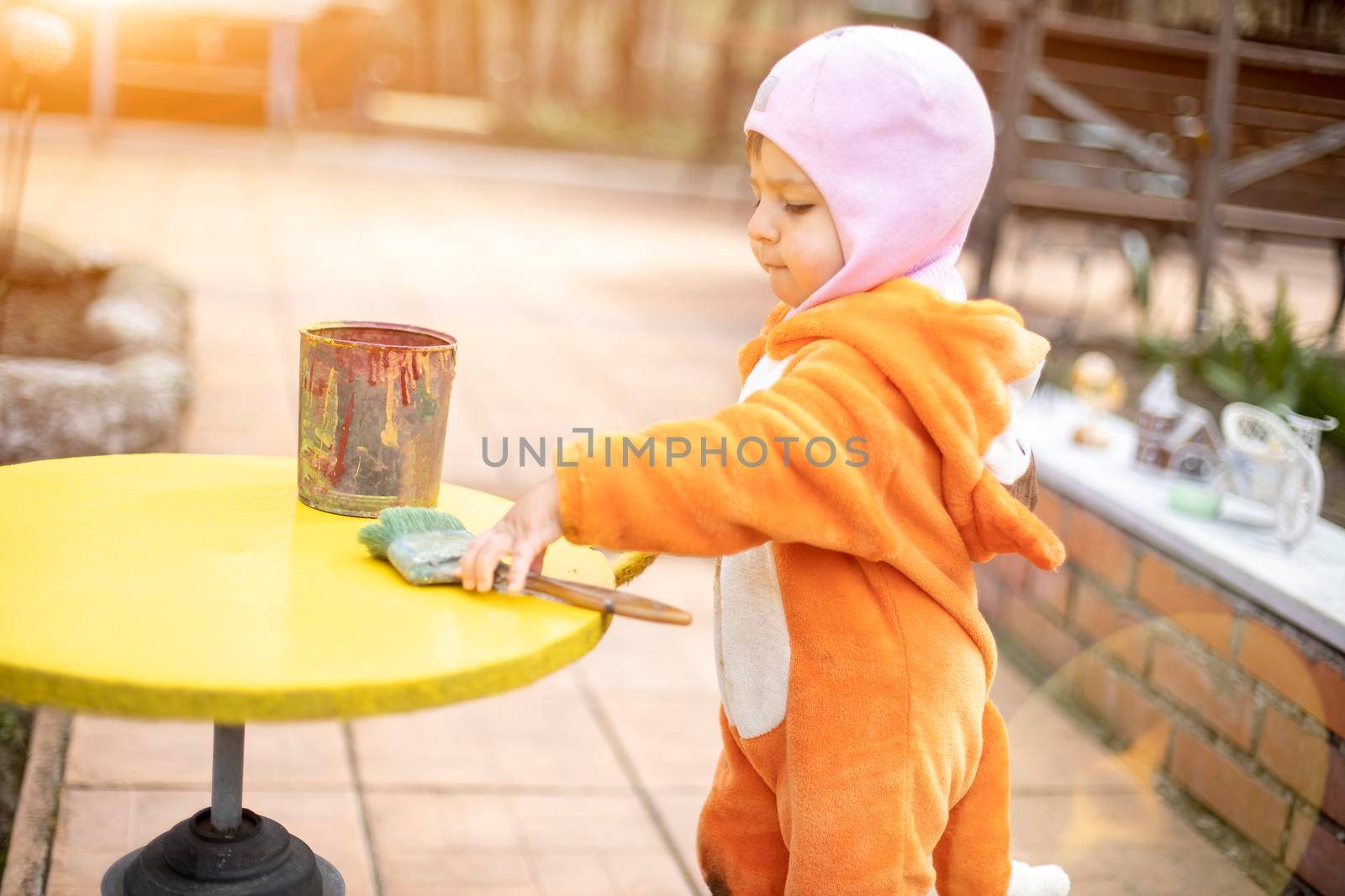 adorable little toddler paints illuminated yellow round table with brush