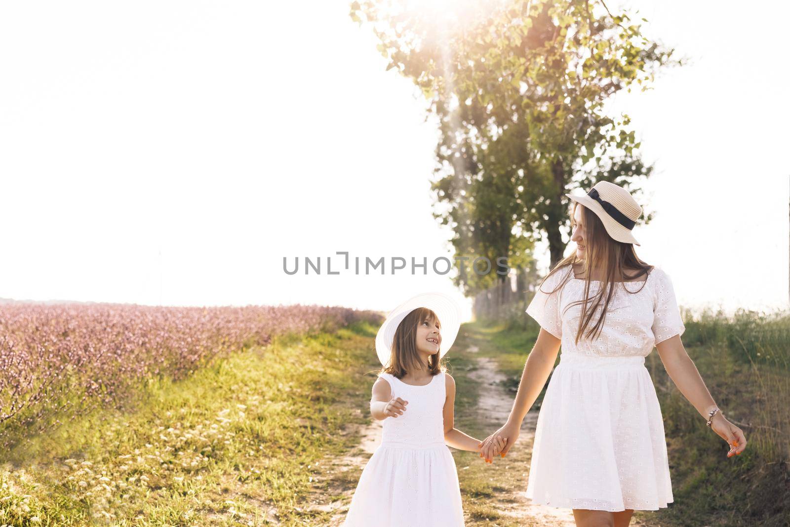 Happy family walks in the park at sunset. Mother and little kid holding hands walking outdoors. Joint family walks healthy lifestyle. Happy family motherhood childhood concept by uflypro