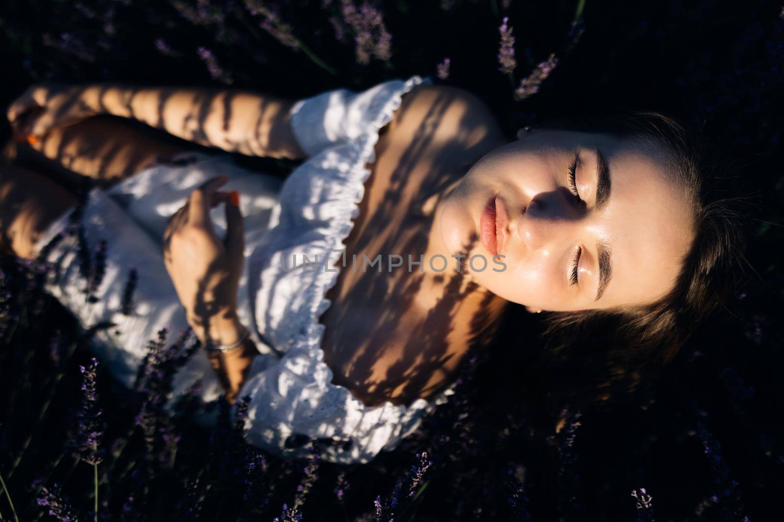 Woman is posing at field of purple lavender flowers. Beautiful woman in the lavender field on sunset in France.