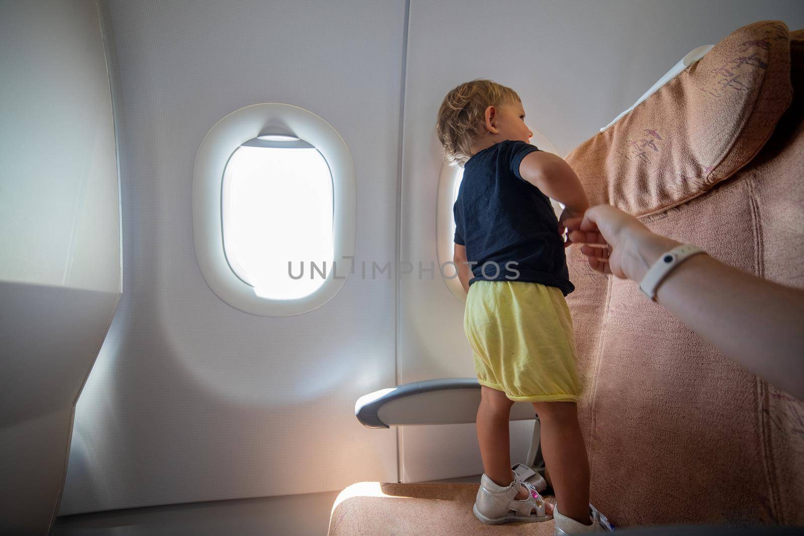 little toddler on the plane stands on the passenger seat dangerous