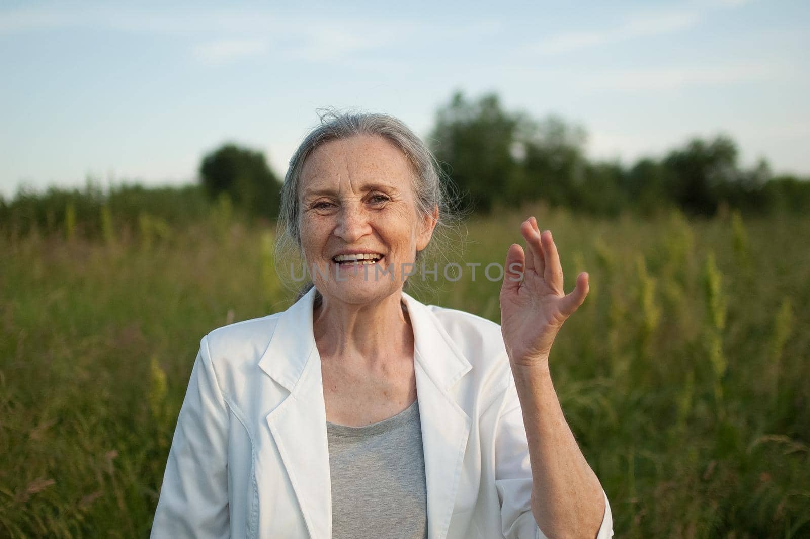 Portrait of senior woman with grey hair and face with wrinkles wearing white jacket and relaxing at park during sunny weather, mothers day by balinska_lv