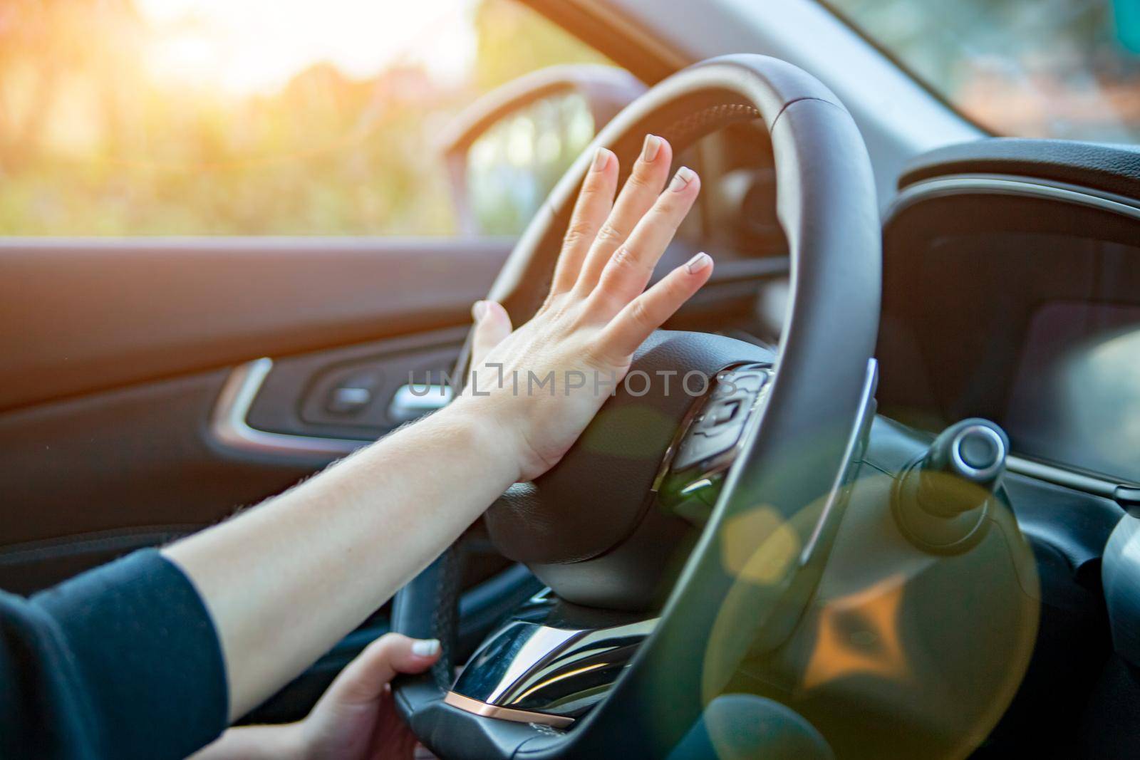 female hand presses the horn on the steering wheel of a modern car. no face