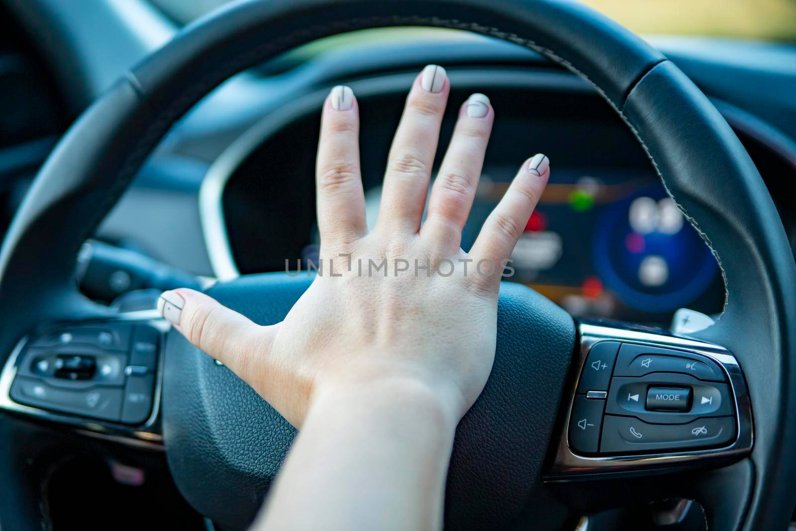 female hand presses the horn on the steering wheel of a modern car. no face