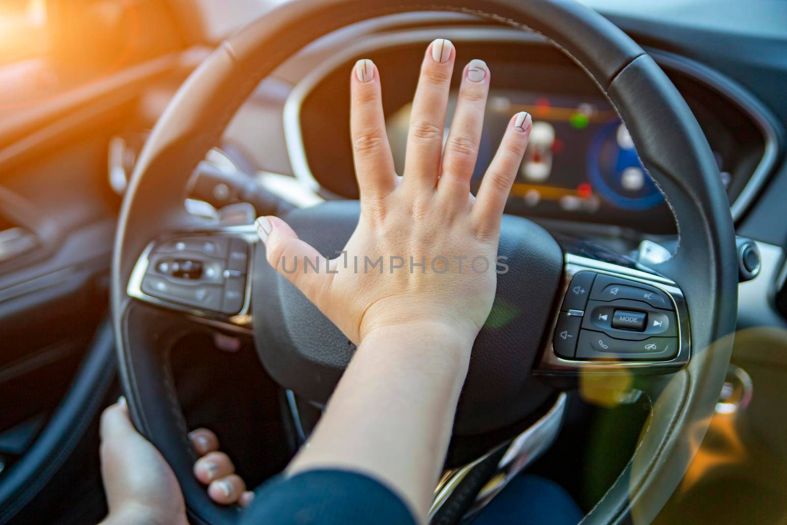 female hand presses the horn on the steering wheel of a modern car. no face