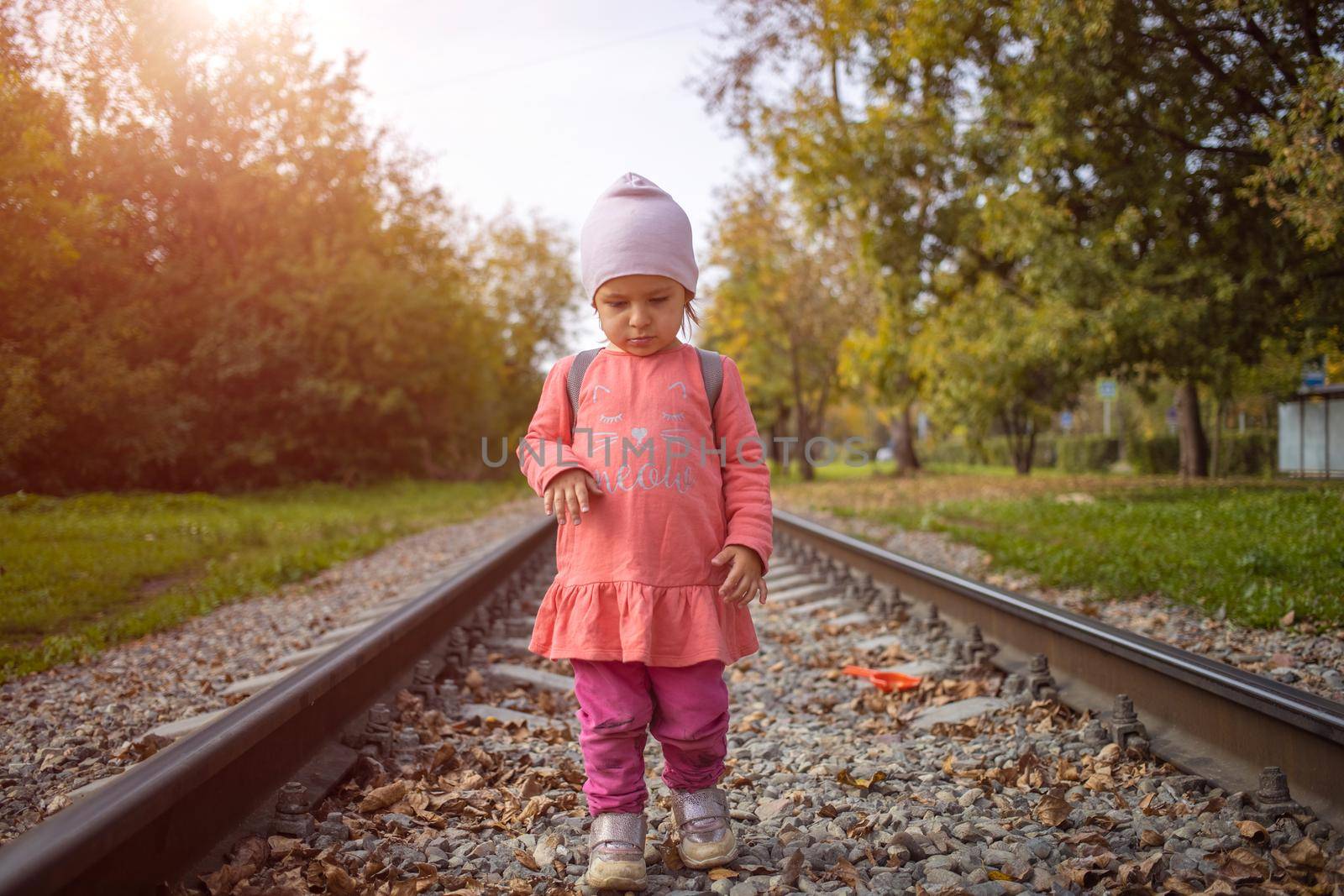 adorable girl walks alone on the railway on a summer sunny day