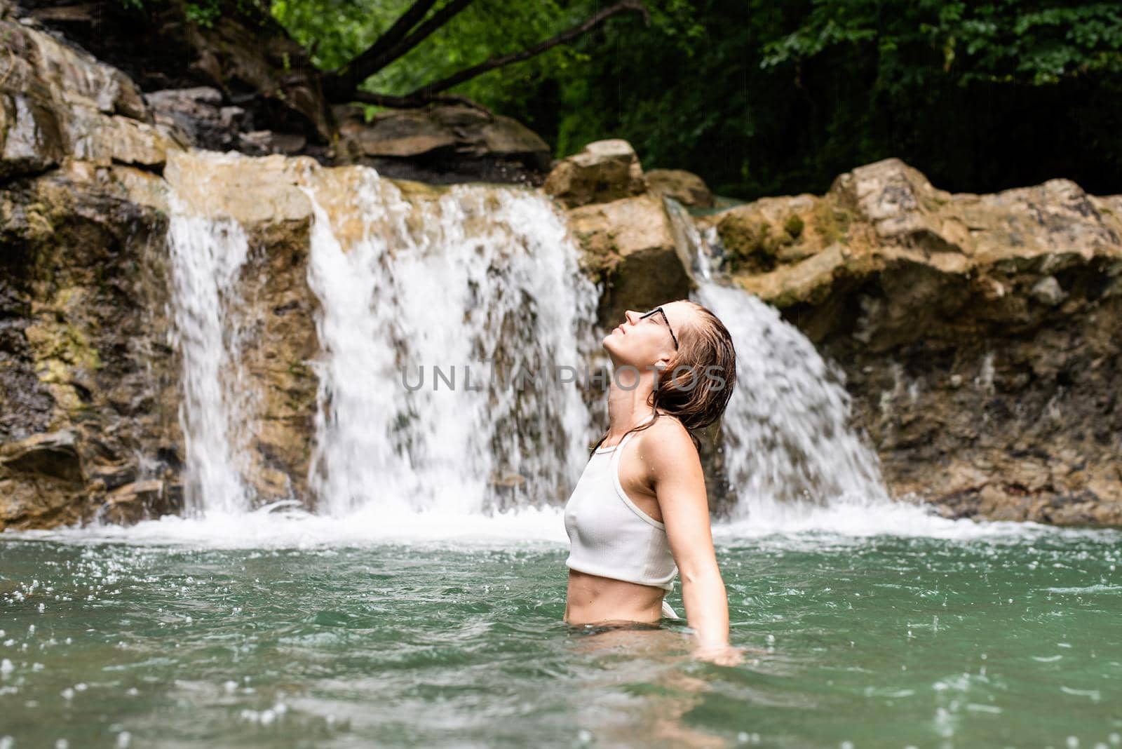 Tropical nature and vacation. Woman swimming in the mountain river with a waterfall