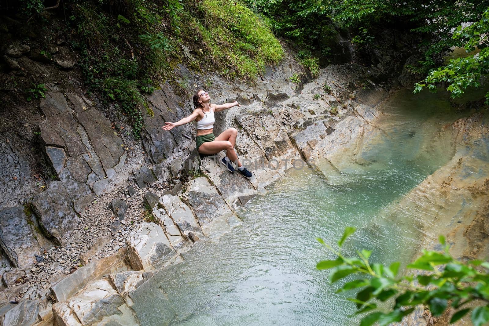 Young happy woman enjoing the nature, sitting by the mountain river. by Desperada