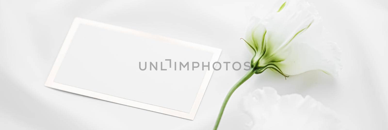 Wedding invitation or gift card and white rose flowers on silk fabric as bridal flatlay background, blank paper and holiday branding, flat lay design concept