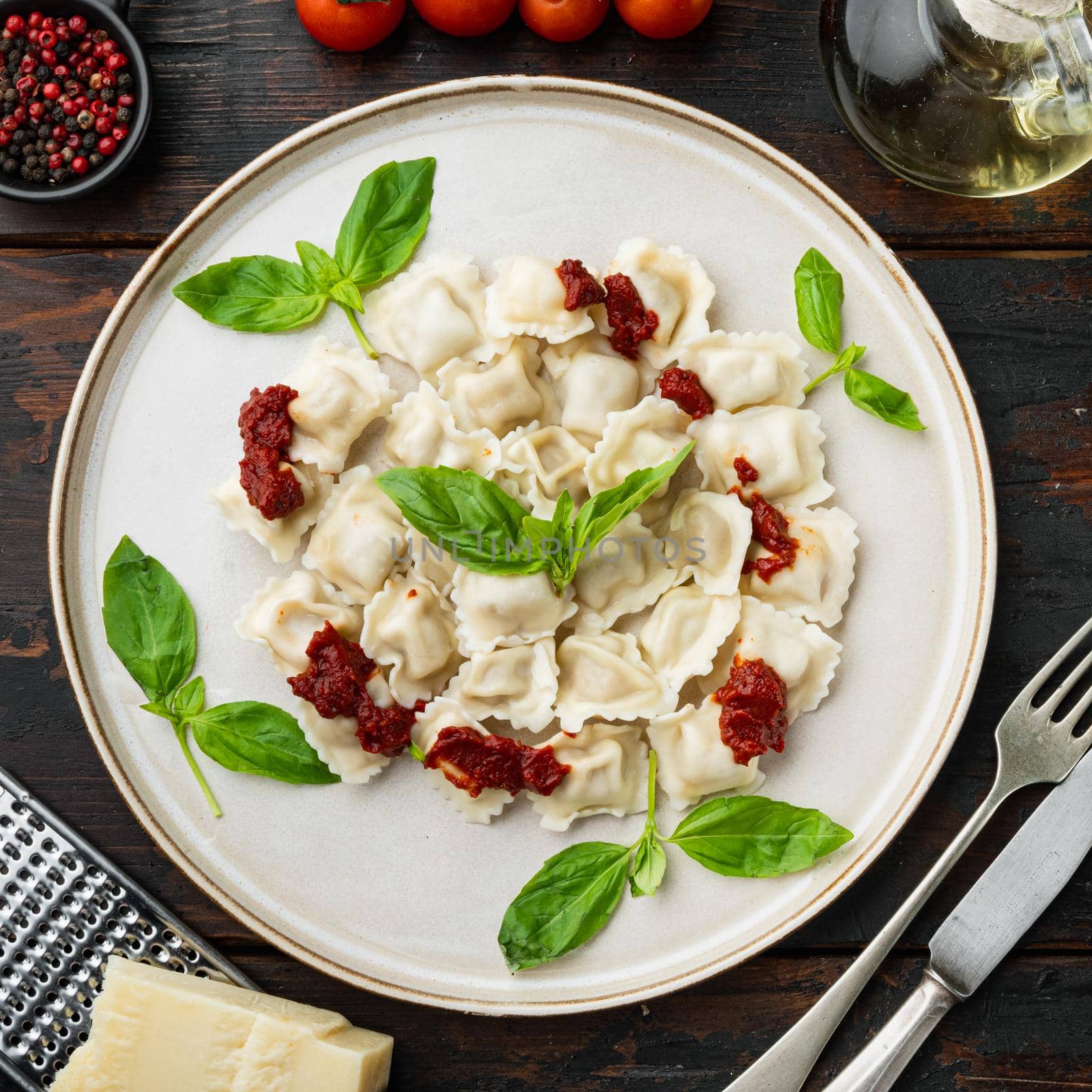 Ravioli pasta with mushroom cream sauce and cheese - Italian food style set with basil parmesan and tomatoe on white plate on old dark wooden table background, top view flat lay