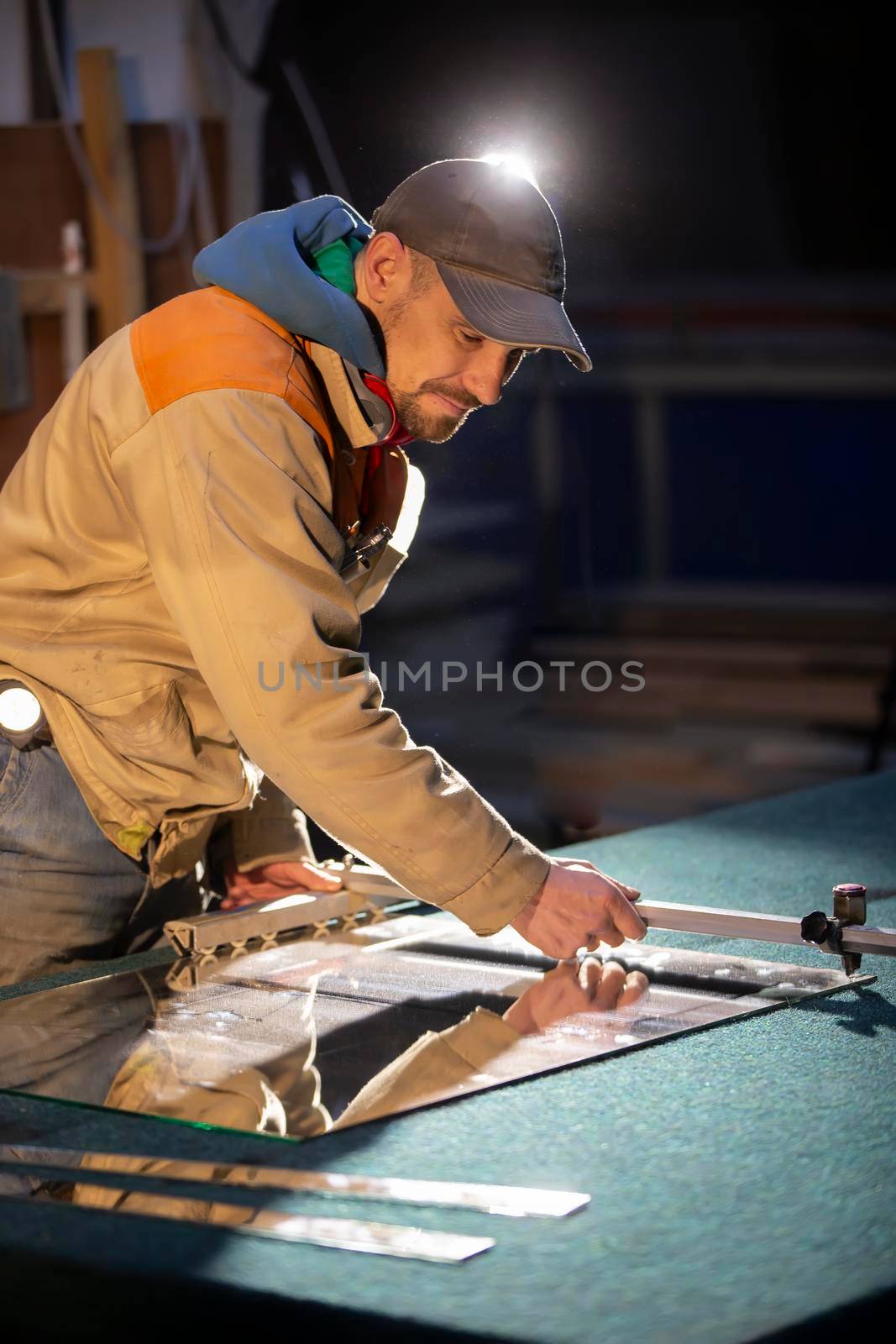 A working man cuts a mirror with a glass cutter.