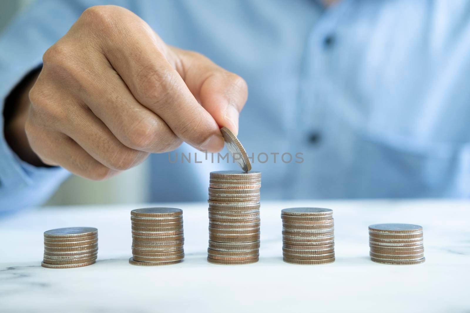 Businessman saving money concept. Hand holding coins putting in jug glass