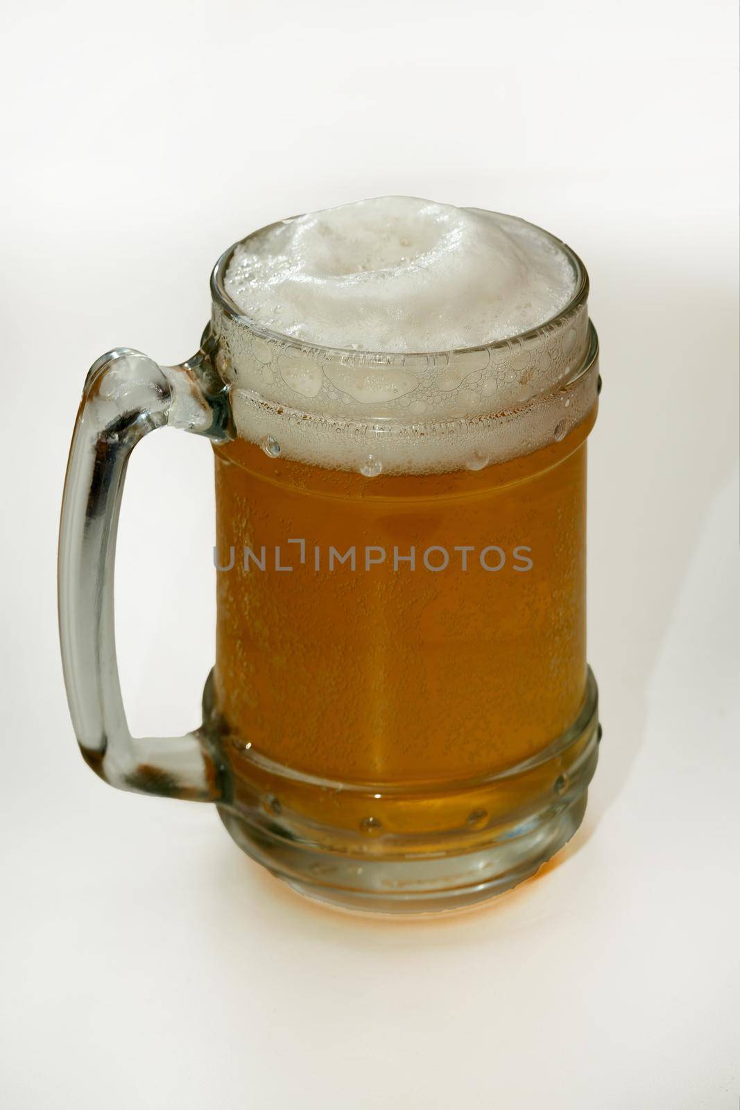 Clear glass with light beer and foam on top. Vertical shot