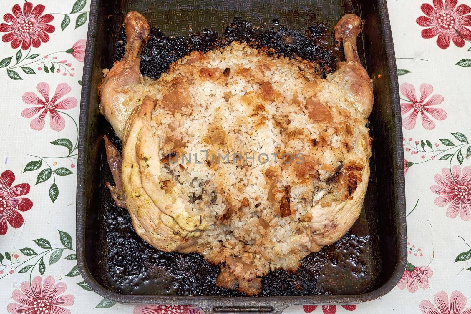 Burnt chicken stuffed with rice on a metal pan. Unsuccessful food preparation