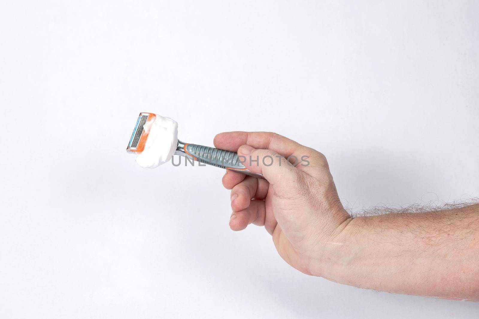 Hand holds a shaving razor with shaving foam on a white background, a template for designers. Close-up