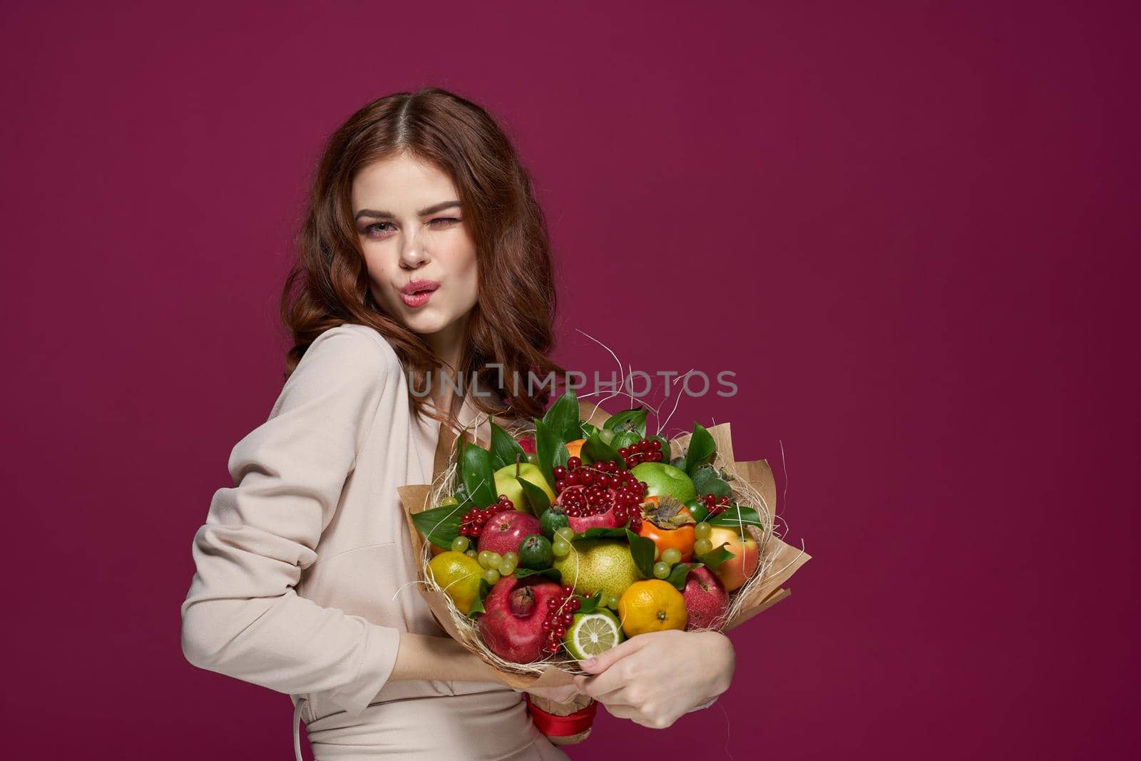 beautiful woman bright makeup attractive look a bouquet of fruits pink background. High quality photo
