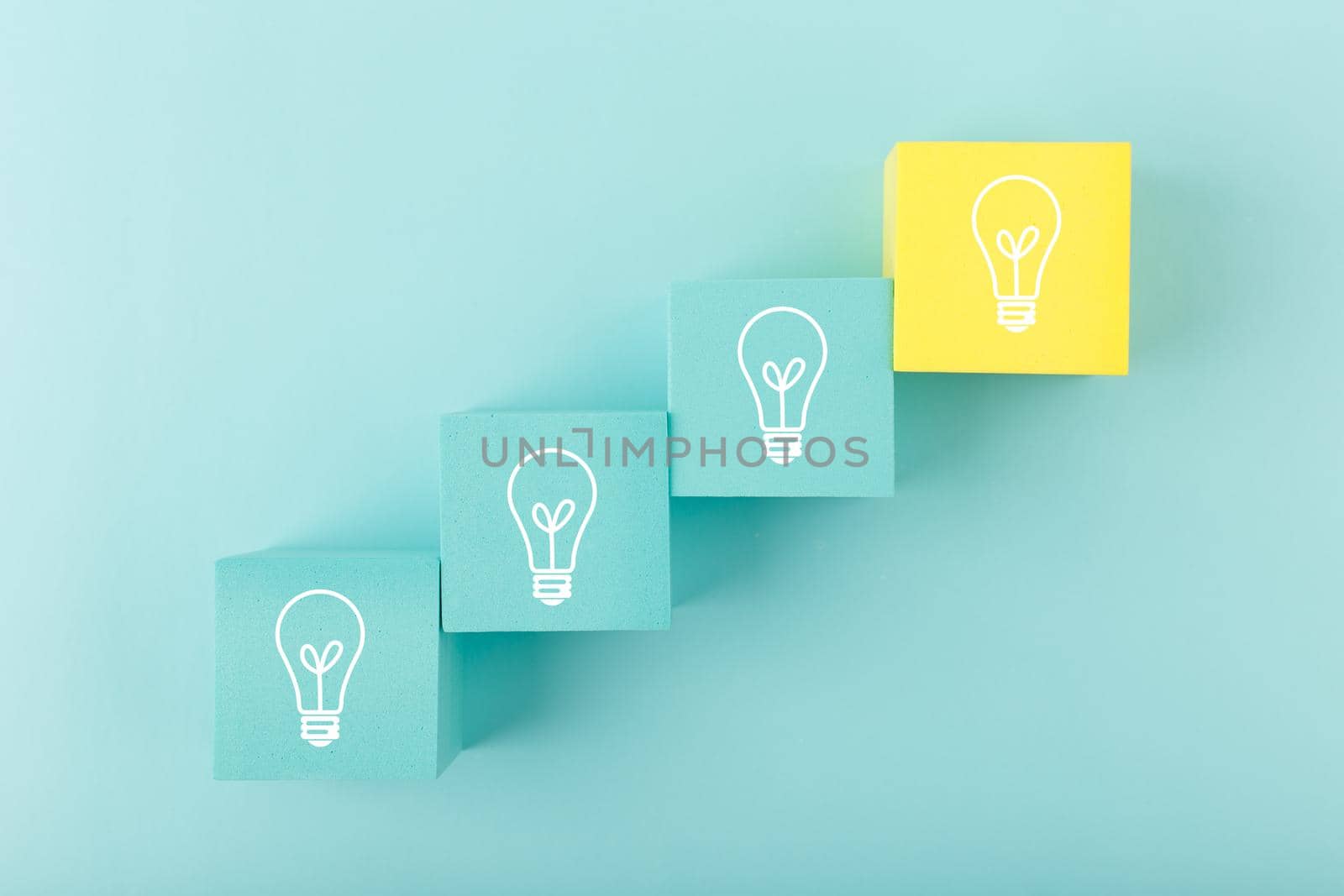 Creativity concept. Light bulbs on blue and yellow toy cubes as a ladder on blue background. Brainstorming and idea developing by Senorina_Irina