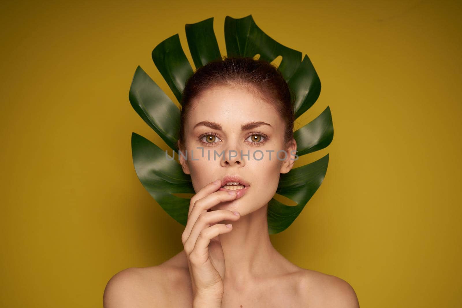 beautiful woman clean skin palm leaf cosmetics yellow background. High quality photo