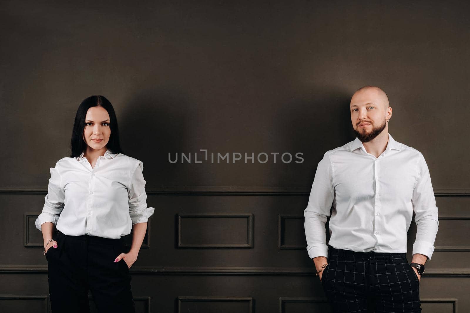 A man and a woman in white shirts on a black background.A couple in love in the studio interior by Lobachad