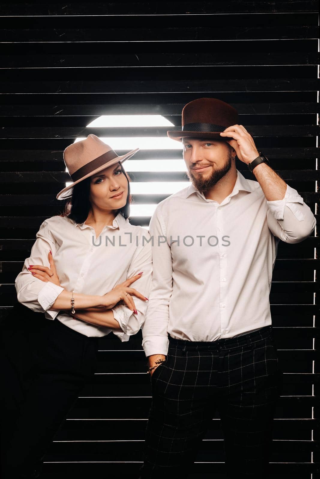 A man and a woman in white shirts and hats on a black background.A couple in love poses in the interior of the studio by Lobachad