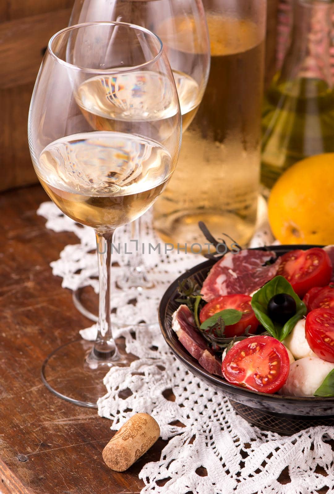 Wine and tomatoes with basil in vintage setting on wooden table