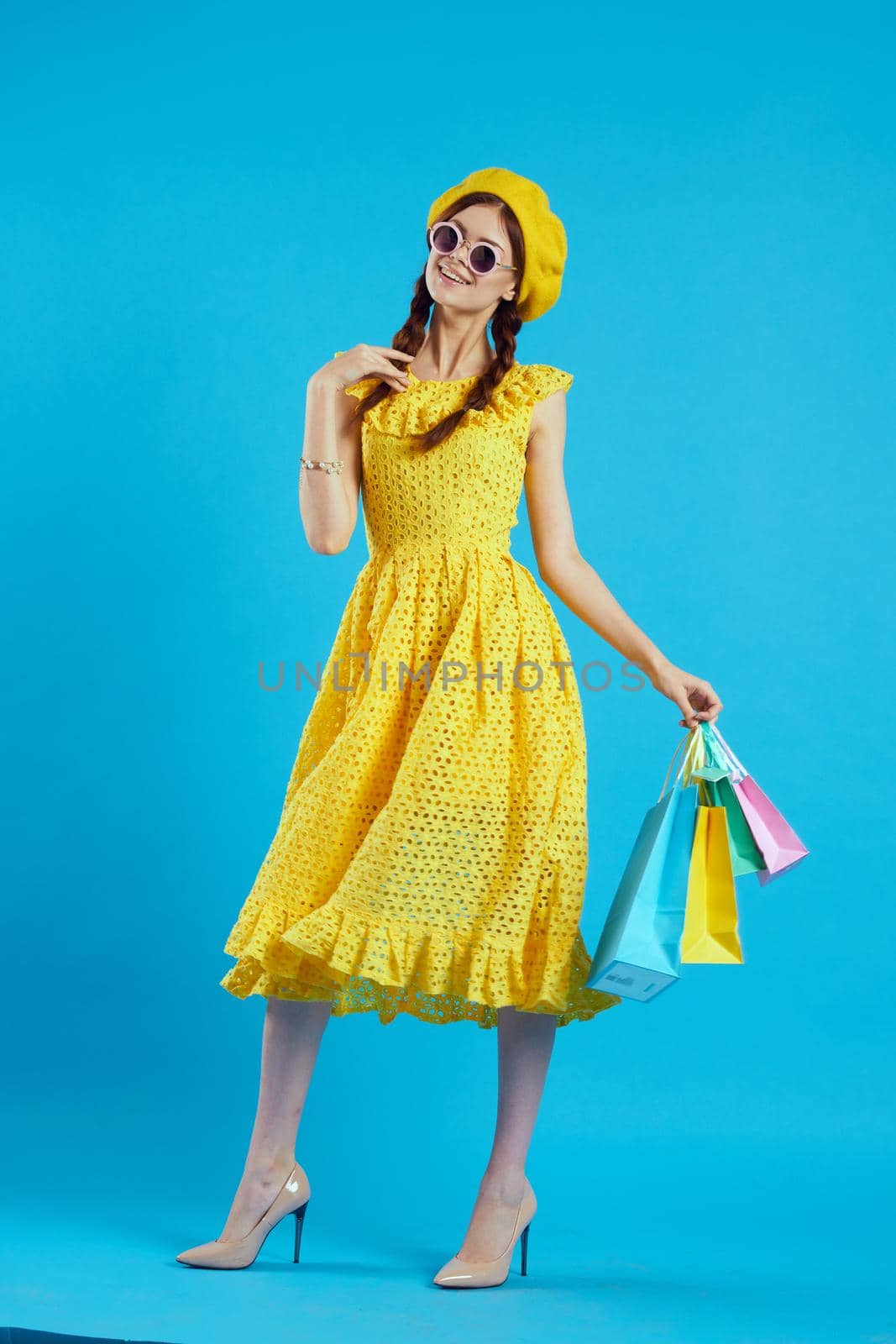cheerful woman yellow dress shopping fun blue background by Vichizh