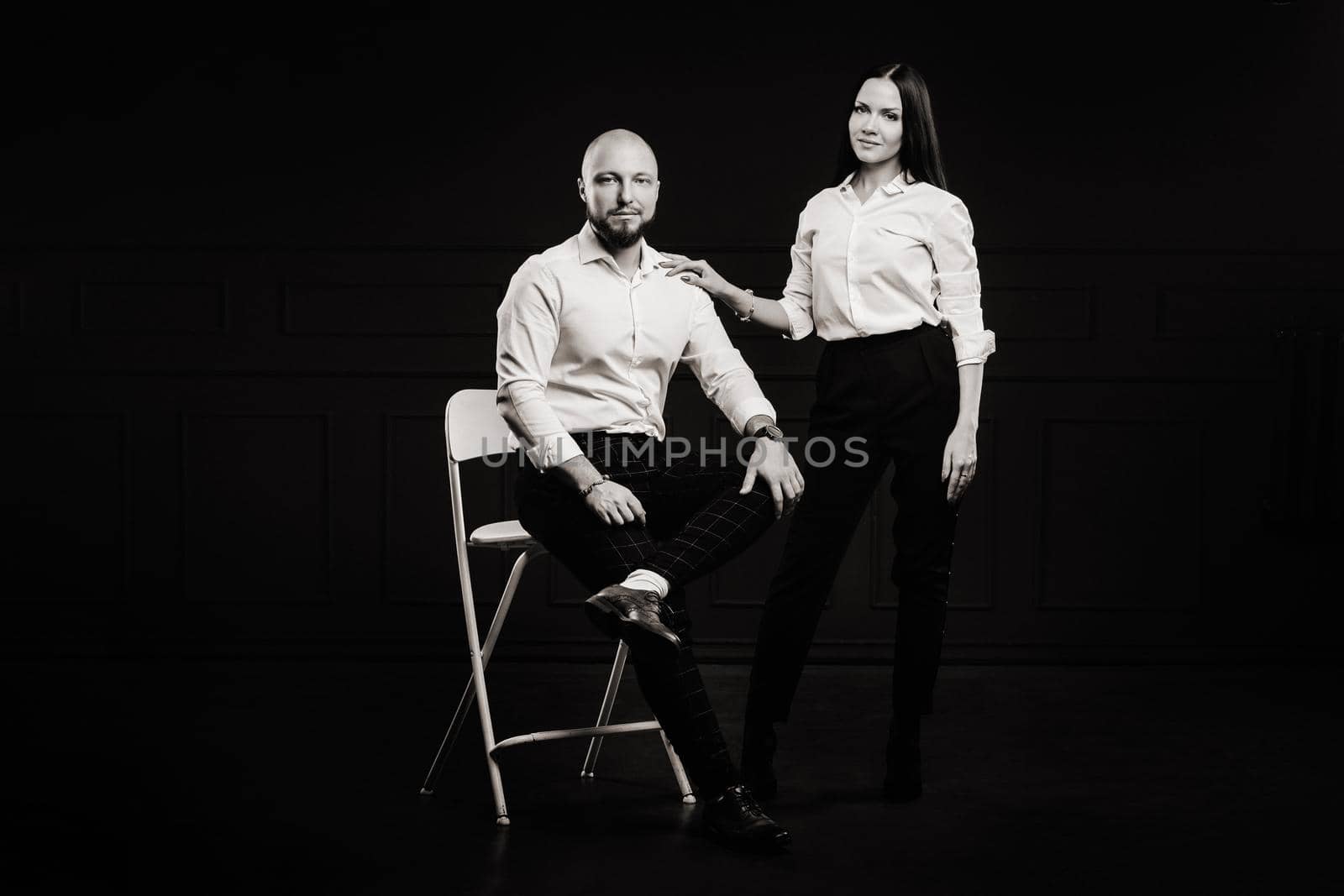 A man and a woman in white shirts on a black background.A couple in love in the studio interior.black and white photo.